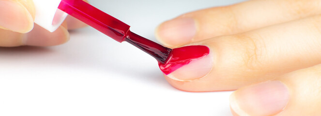 Woman applies red nail polish..Girl making a manicure. Salon procedures at home. Beautiful hands and nails. Close up, macro photo.