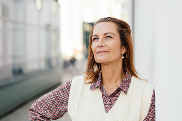 Attractive middle-aged woman standing daydreaming with a smile