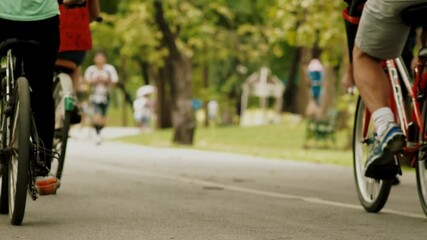 Crowd of urban population enjoying early morning walk, exercising and riding bicycle early in park during the weekend break recreational activities