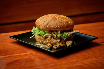 Juicy mussels burger with salad and sauce. On a plate with fries. wooden background