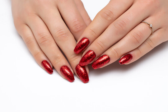 Gel manicure red glitter on long nails. Bolero nail shape. Close-up, white background.