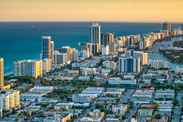 Aerial view of Miami skyline and tall skyscrapers from helicopter at sunset.