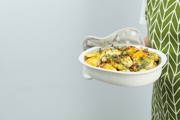 Woman holds baking tray with baked cauliflower