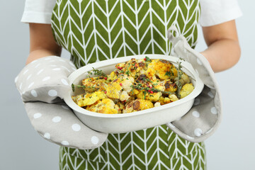 Woman holds baking tray with baked cauliflower