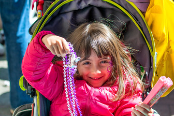Happy smiling young girl wearing beads in Mardi Gras Carnival Parade, New Orleans.
