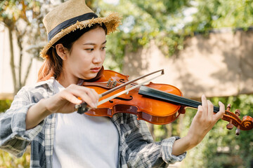 Close-up portrait of Young Asia woman music violinist play violin, relax in the garden with peace...