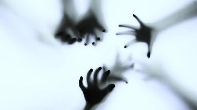 Silhouette of a zombie hand on white background in slow motion
