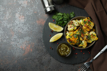 Concept of tasty food with baked cauliflower on dark textured background