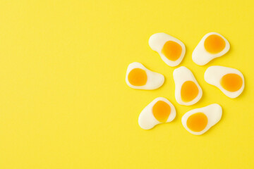Gummy candies on yellow background, space for text