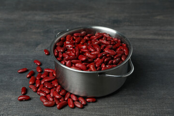 Pot with red beans on gray background