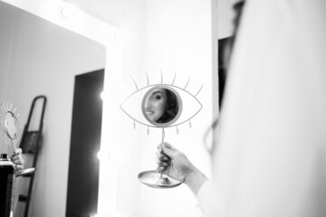 The bride looks at herself in the mirror. Black and white photo