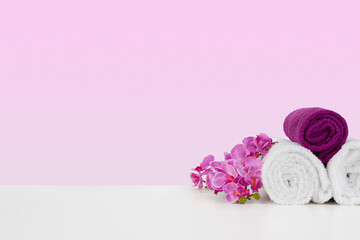 Beautiful pink flowers and white towels on pink background