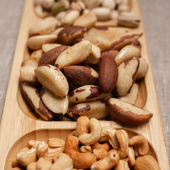 High angle of heap of cashew and Brazil nuts placed on wooden plate on table 
