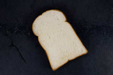 White bread slice isolated on black stone. 
