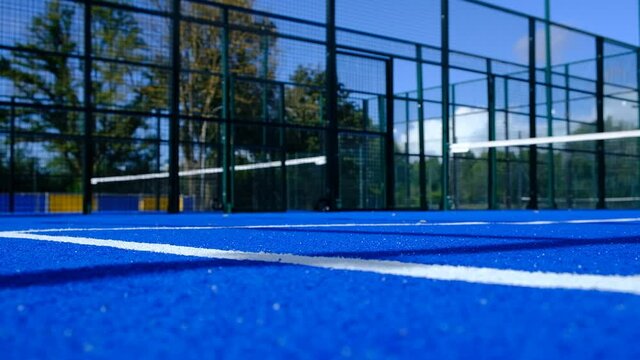 static view of an empty paddle tennis court and two bouncing balls
