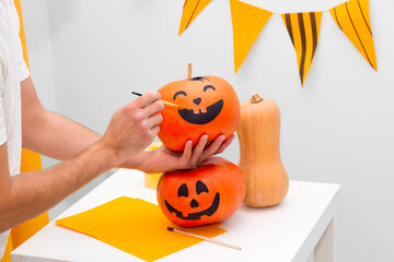 Holiday preparation and handmade party decor. Halloween indoor activity, pumpkin painting process
