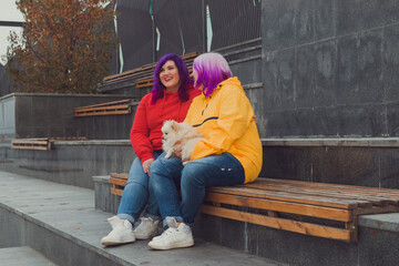 two color hair lesbian woman sitting on bench outdoor, holding cute dog spitz