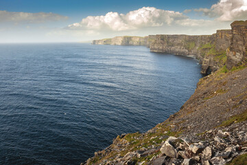 Fototapeta na wymiar Spectacular scenery of Cliff of Moher, county Clare, Ireland. Warm sunny day. cloudy sky. Irish landscape.