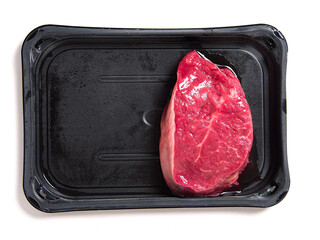 One fresh raw piece of fillet steak on a black plastic tray and a red heart. Love meat theme. Butcher product. High quality beef cut. White isolated background. Meat industry