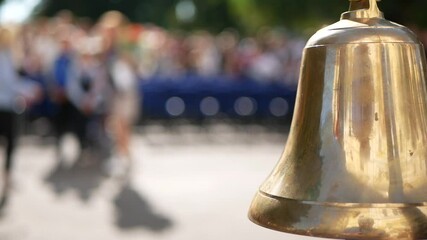 knowledge day at school golden school bell waving in the foreground close-up in the background people walking out of focus