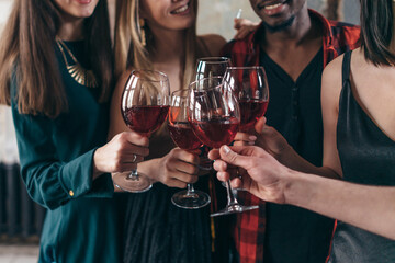 People enjoying drinks at cafe. Friends at bar toasting wine and smiling