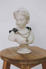 A chic necklace made of leather and chain hangs on a plaster figure