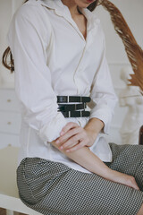 Young girl in a white office shirt trying on a leather belt