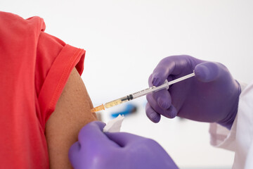 Close up of a doctor's hand injecting a vaccine in the shoulder of patient. Coronavirus covid-19 vaccination concept