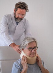 Senior woman in pain wearing a cervical collar with the assistance of her physiotherapist doctor