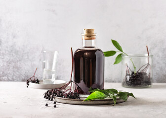 Delicious black elderberry liqueur in a glass bottle. Homemade food concept. Copy space. - obrazy, fototapety, plakaty