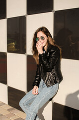 Portrait of a fashionable smiling young woman with sunglasses on the street