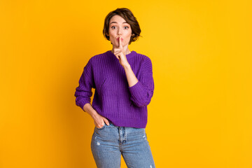 Portrait of attractive mysterious girl showing shh sign mute info isolated over bright yellow color...