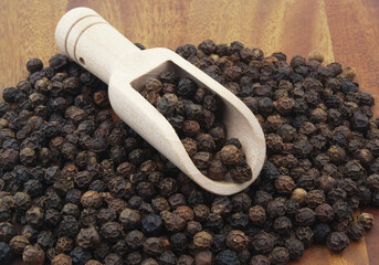 Black pepper with wooden scoop close up