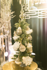 Close up of green gold Christmas tree with big toys on gold table