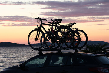 Naklejka na ściany i meble Bicycles by car on a sunset background