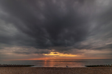 Landscape orientation shot of a sunrise in Eastbourne, East Sussex, United Kingdom, long exposure shot showing movement of clouds and dramatic skies and the pier, wide angle shots,