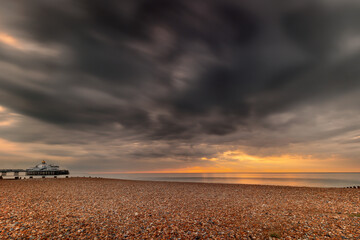 Landscape orientation shot of a sunrise in Eastbourne, East Sussex, United Kingdom, long exposure shot showing movement of clouds and dramatic skies and the pier, wide angle shots,
