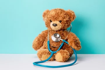 Foto op Plexiglas Pediatrics. Teddy bear with a stethoscope. Teddy bear on a green background © adragan