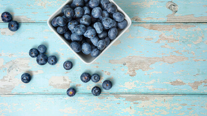 A top view, flatlay, overhead view of blueberries on a blue wooden textured background with space for text, 