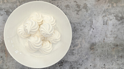 An overhead flatlay shot with meringues shot on a grey textured background, portrait orientation