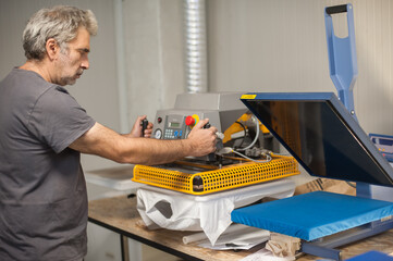 Print technician work on digital t-shirt printing heat press machine
