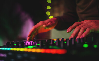 DJ Hands creating and regulating music on dj console mixer in concert nightclub