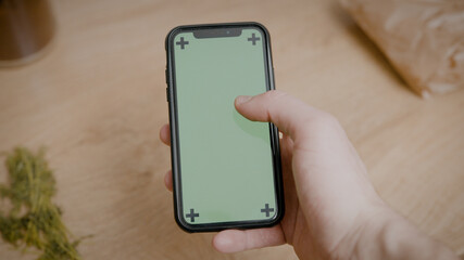 Person Holding A SmartPhone Scrolling Trough Social Media Green Screen Background In The Kitchen