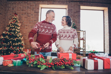 Photo of positive married couple wrapping x-mas presents man hold scissors wear ornament pullover home indoors