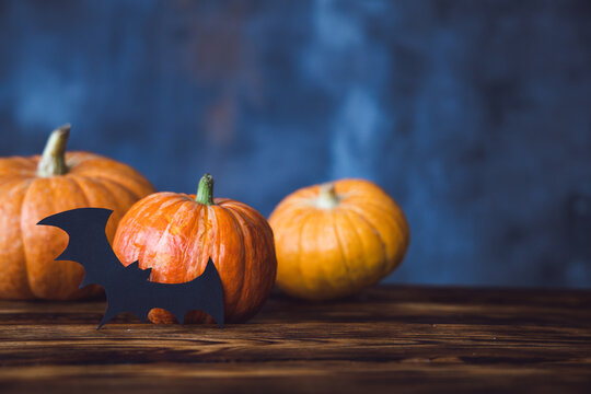 Halloween, three pumpkins on the table, bat, place for text. High quality photo
