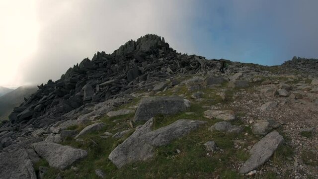 A man walking beside a pile of rocks on Glyder Fawr in the Snowdonia mountains