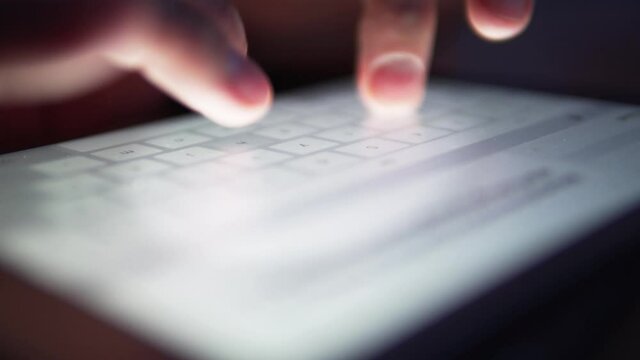Fingers quickly typing on a tablet. Business emailing on a touch screen device. Research work on digital tablet