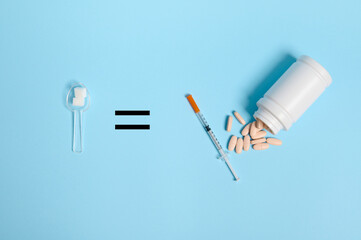 Top view of insulin syringe and pharmaceutical pills scattered from container on blue background, equal sign and measuring spoon with white sugar cubes, copy space for World Diabetes Awareness Day. Ad