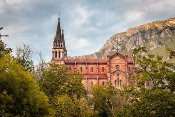 Fototapeta na wymiar Basílica de Covadonga, Principado de Asturias, España. Vista lejana con arboleda delante y montaña detrás.