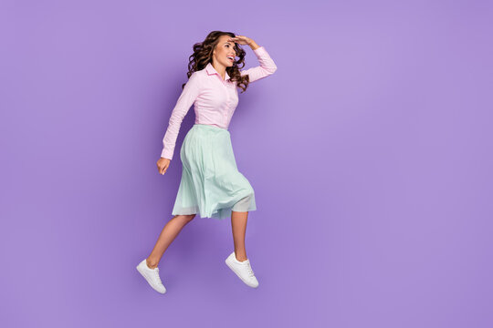 Full length profile photo of impressed young brunette lady run look wear shirt skirt sneakers isolated on violet background